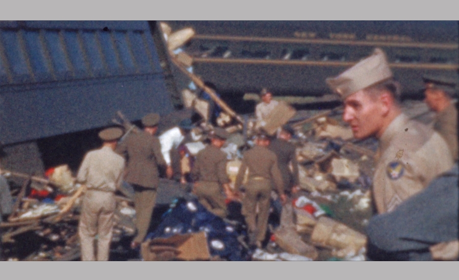 soldiers sort through debris in front of a tattered black train car